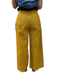 Mustard yellow wide-leg pants worn by a woman on a white background. woman is wearing size large