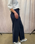 Person wearing navy wide-leg pants and a light-colored top against a plain background