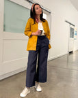 Person wearing a mustard yellow jacket and dark blue pants in an indoor setting