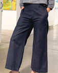 Person wearing navy wide-leg pants and a gray top in an indoor setting.