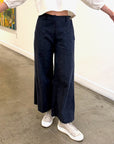 Person wearing dark blue wide-leg pants and white sneakers indoors.