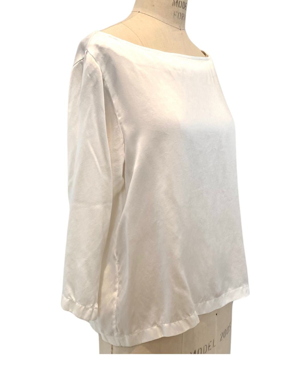 The white Lucia top shown on a dress form, side view
