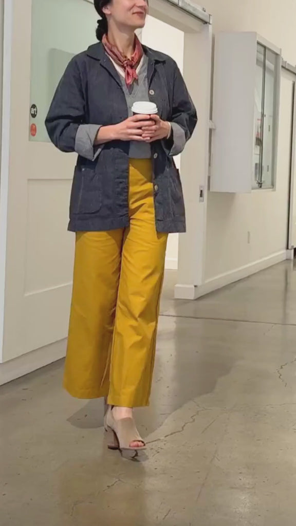 Video of woman wearing mustard yellow pants walking slowly in an art gallery