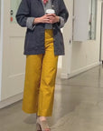Video of woman wearing mustard yellow pants walking slowly in an art gallery